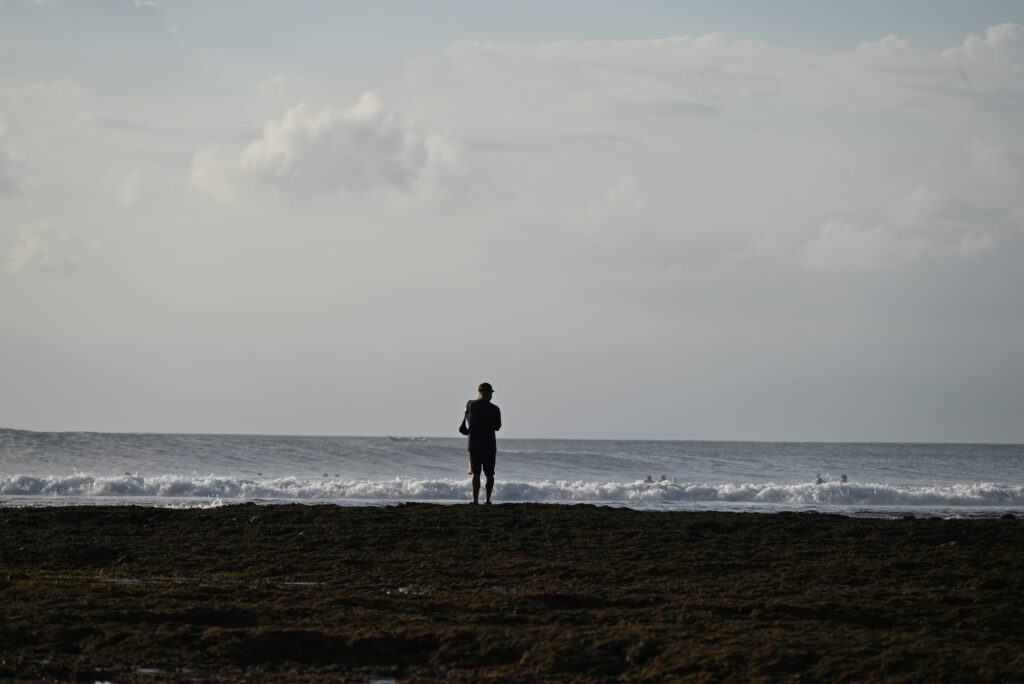 Man standing on shore, gazing at the ocean horizon